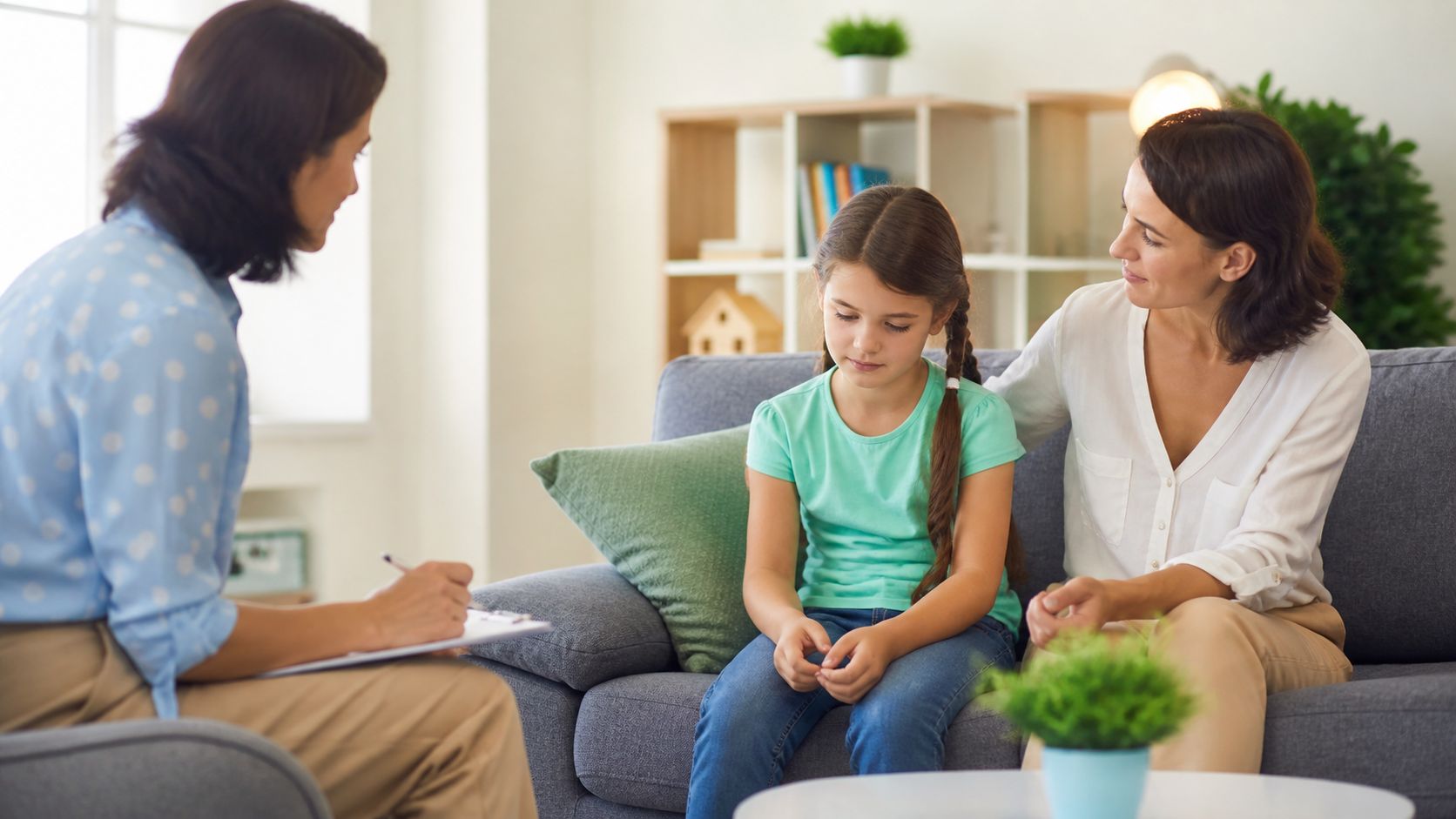 Child receiving support for social anxiety during a counselling session with a parent and psychologist